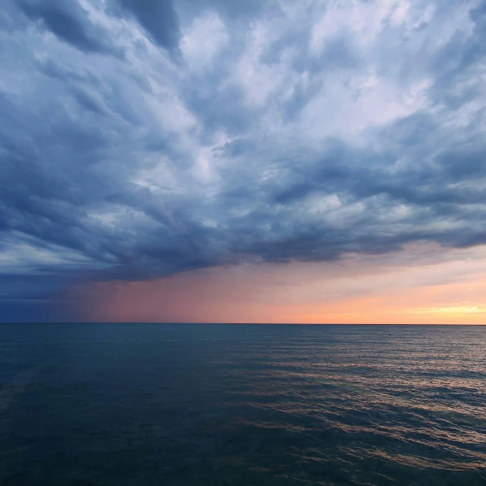 a body of water with a cloudy sky above it